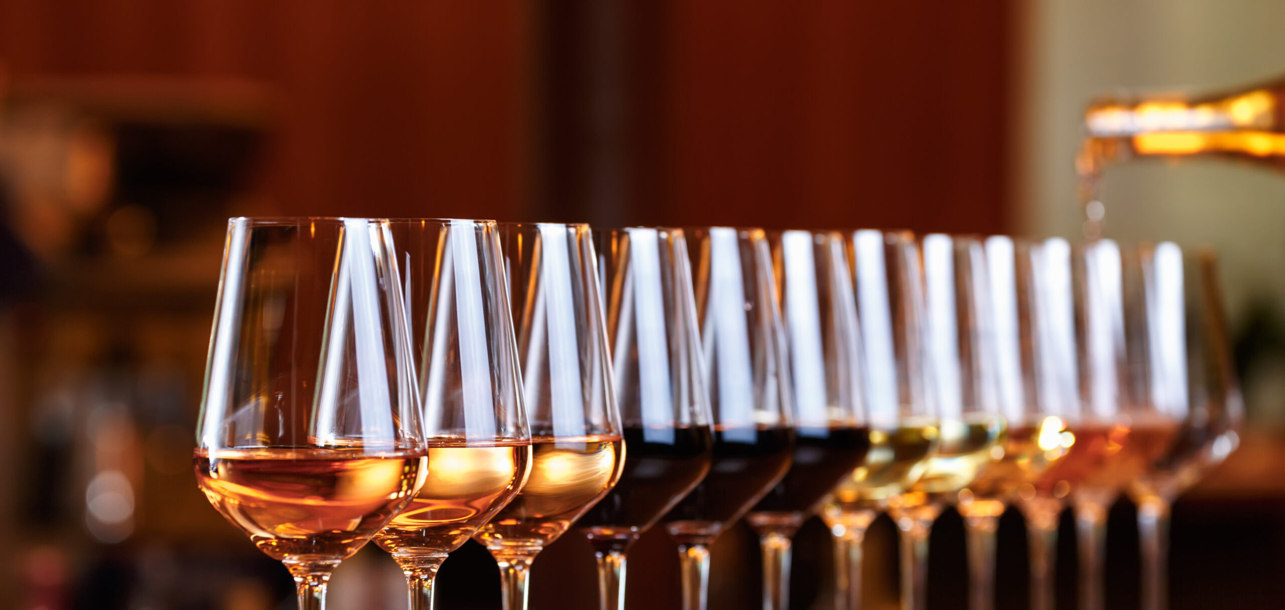 Wine glasses in a row. Pouring wine. Buffet table celebration of wine tasting. Nightlife, celebration and entertainment concept. Horizontal, wide screen banner format